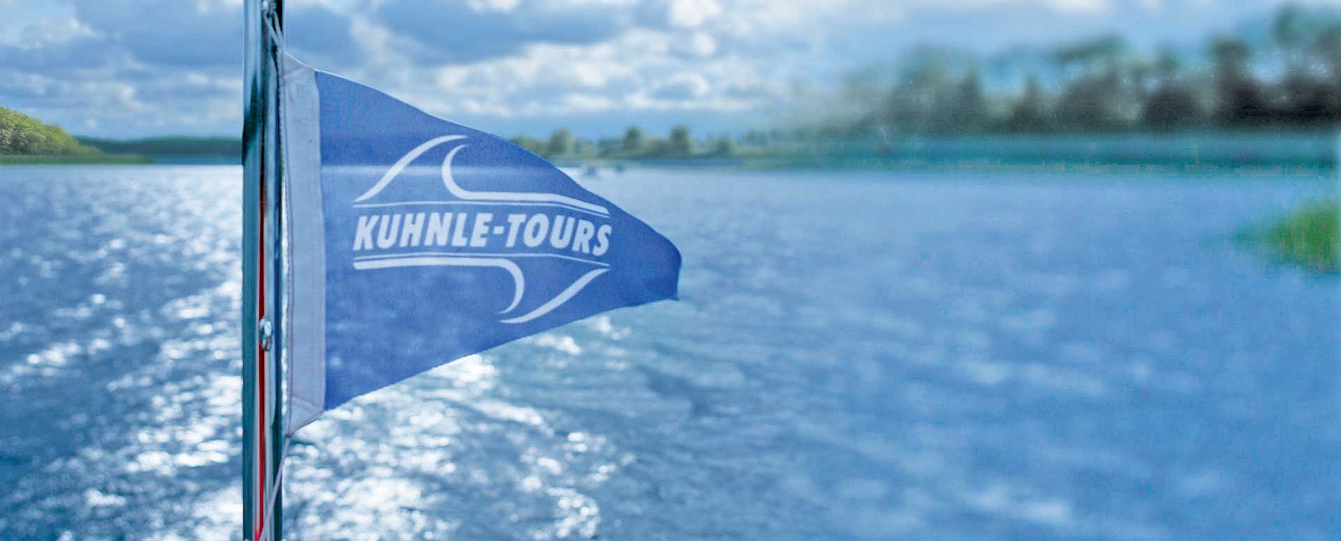 die Fahne von KUHNLE-TOURS flattert im Fahrtwind auf einem Hausboot